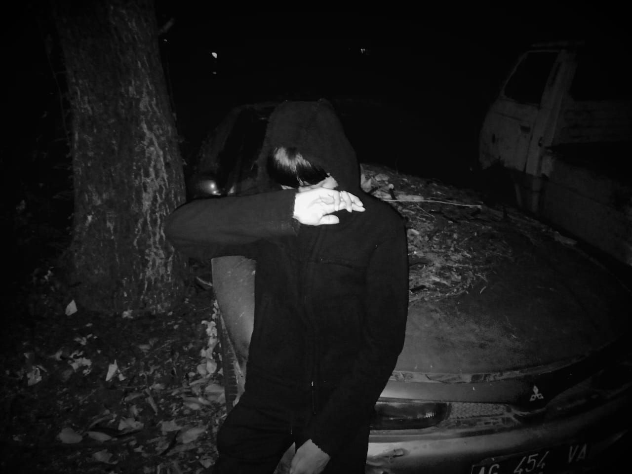 Foto fashion hitam putih Kirei berhoodie di depan mobil tua pada malam hari